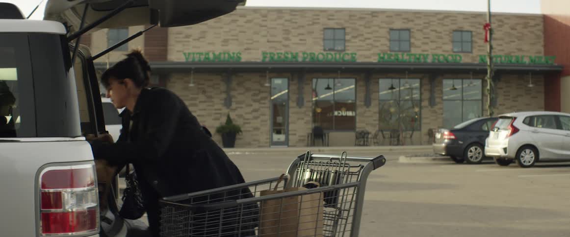 A woman unpacks groceries into her car