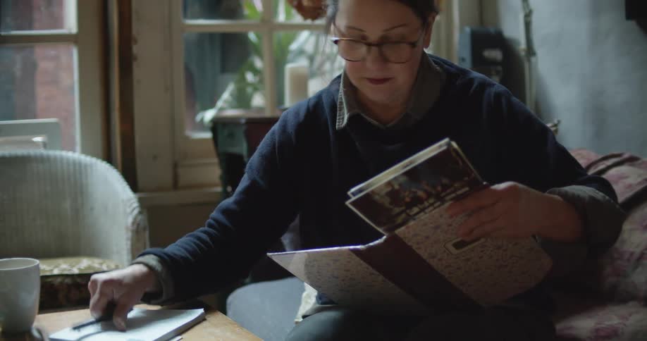A woman looks at photos on the couch