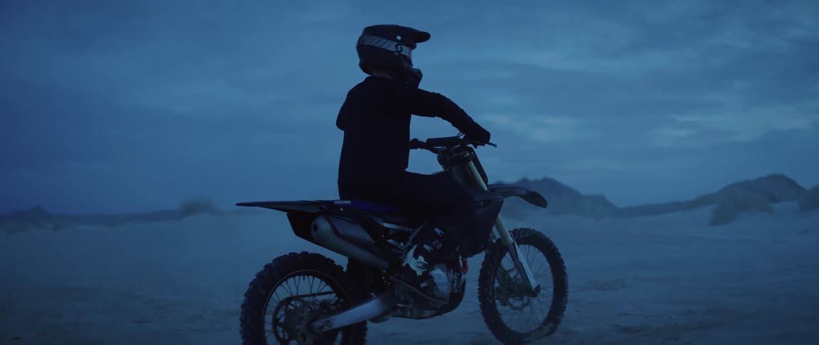 A man sits on his dirt bike while looking out over an expansive desert