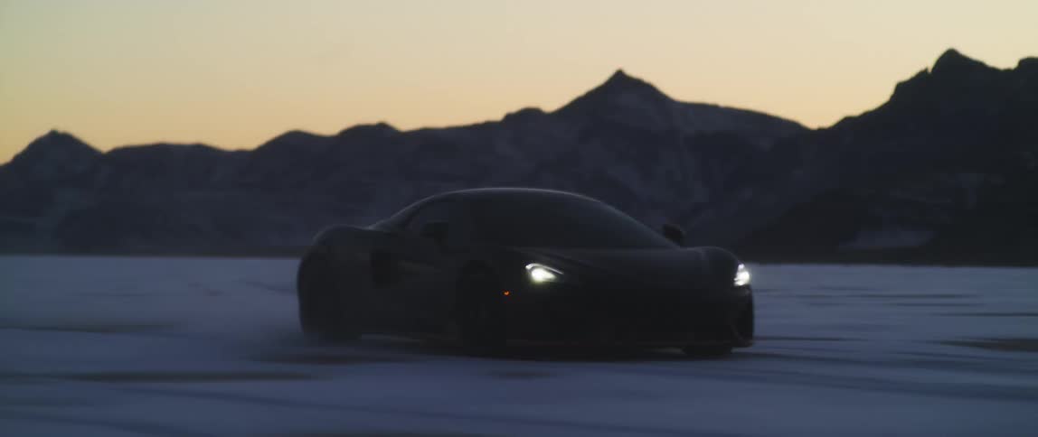 A vehicle driving on a landscape with a mountain range the sky and clouds in the background
