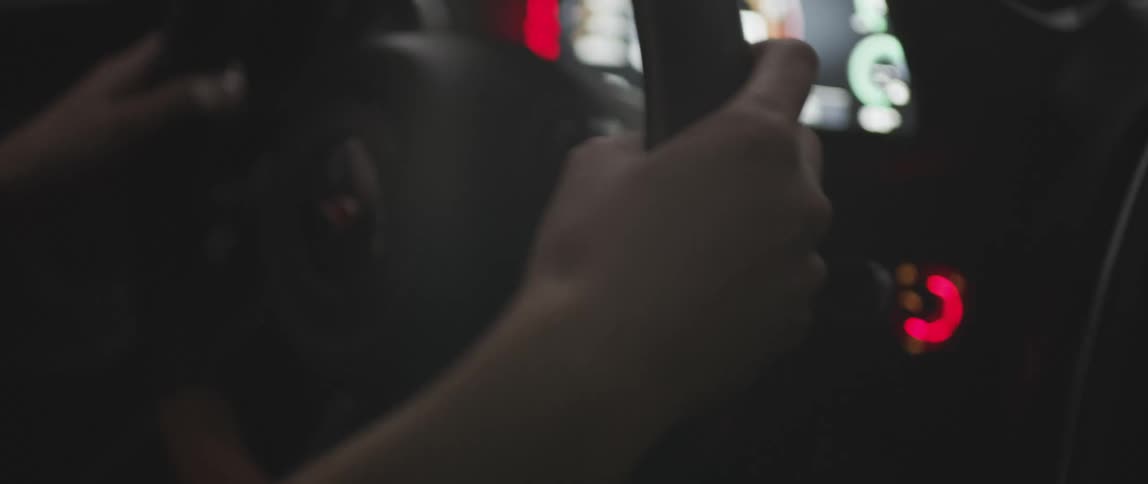Hands swerve the steering wheel of a sportscar