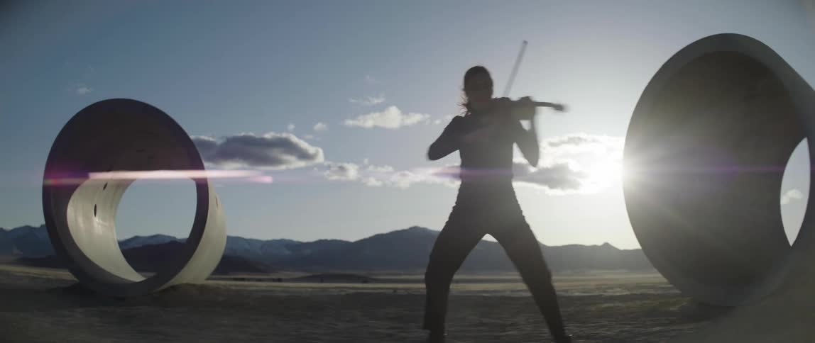 A female violinist plays and walks around concrete pipes as the sun shines