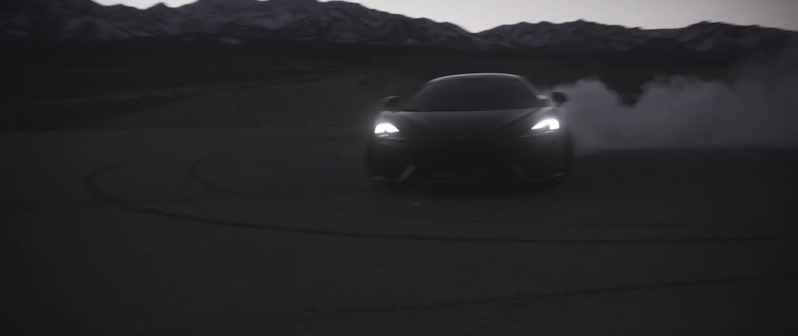 A sports car doing donuts in the desert kicks up dirt as it spins