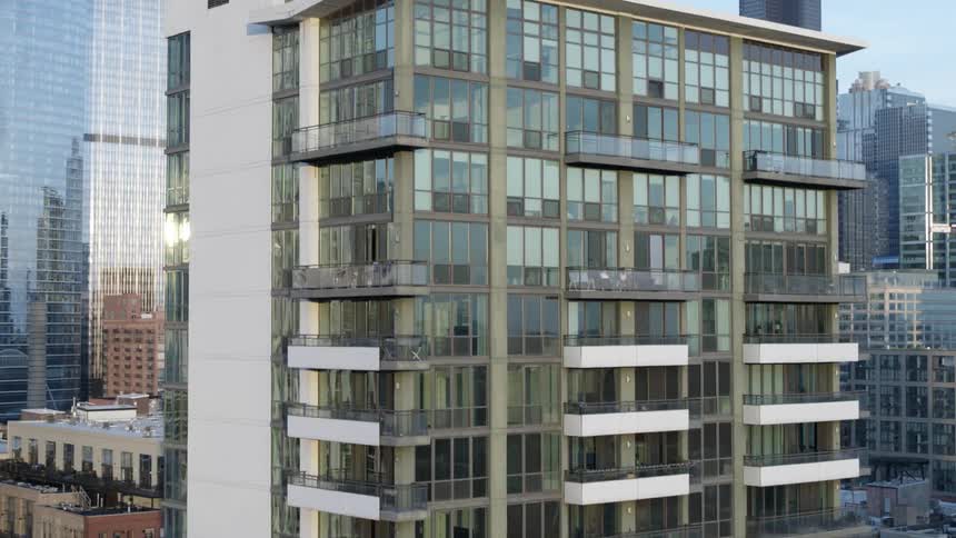 Mirrored windows cover the front of a tall condo building downtown