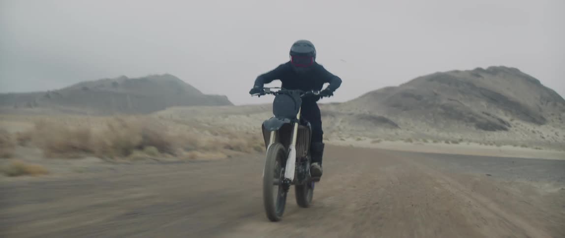 Motorcyclists rides a motorcycle at a high speed on a dirt road near the mountains
