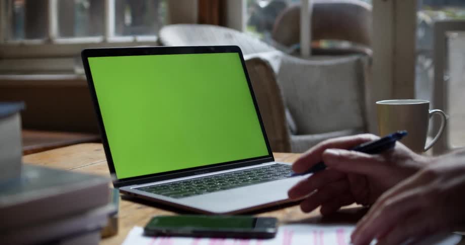 Hands gesture take notes and pick up a phone with an open laptop on a coffee table