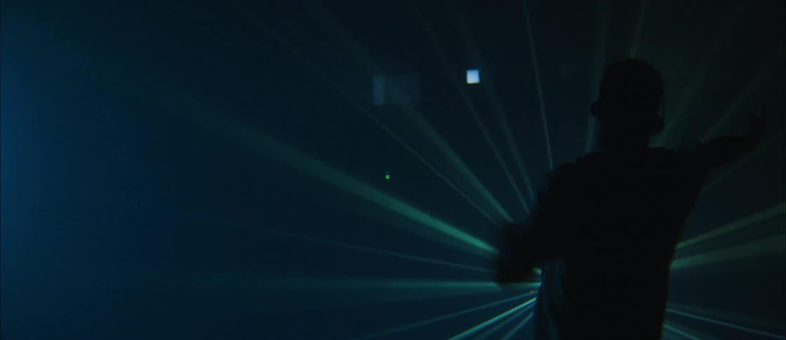 A man dancing in front of a laser on a stage