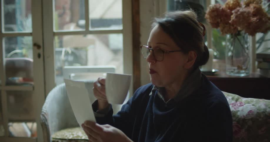 A woman sitting in a house drinking coffee