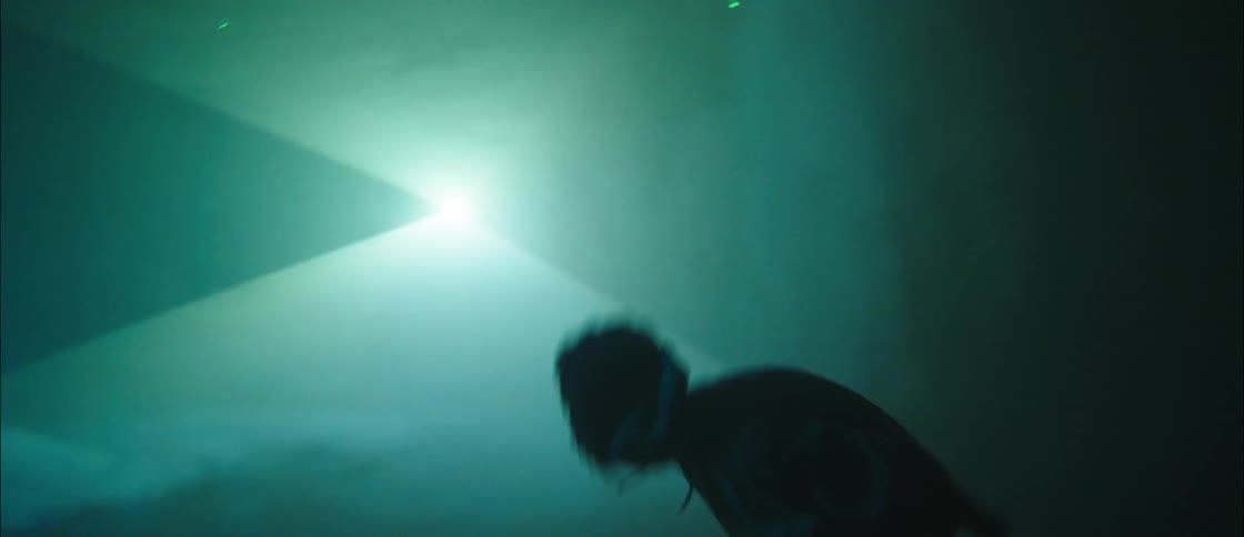 A silhouette of a man with headphones dancing in a room with a spotlight in the background