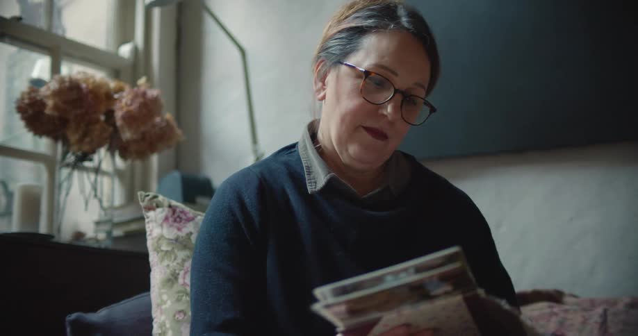 A woman sits at home and looks through a book of photos
