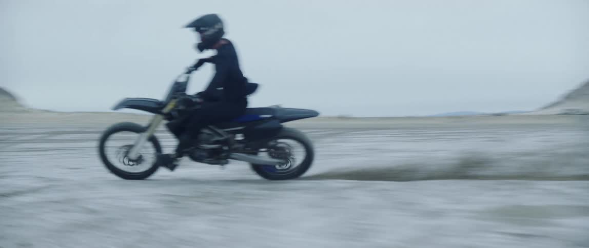 A person on a dirt bike makes a sharp turn as they race through a wide open desert area