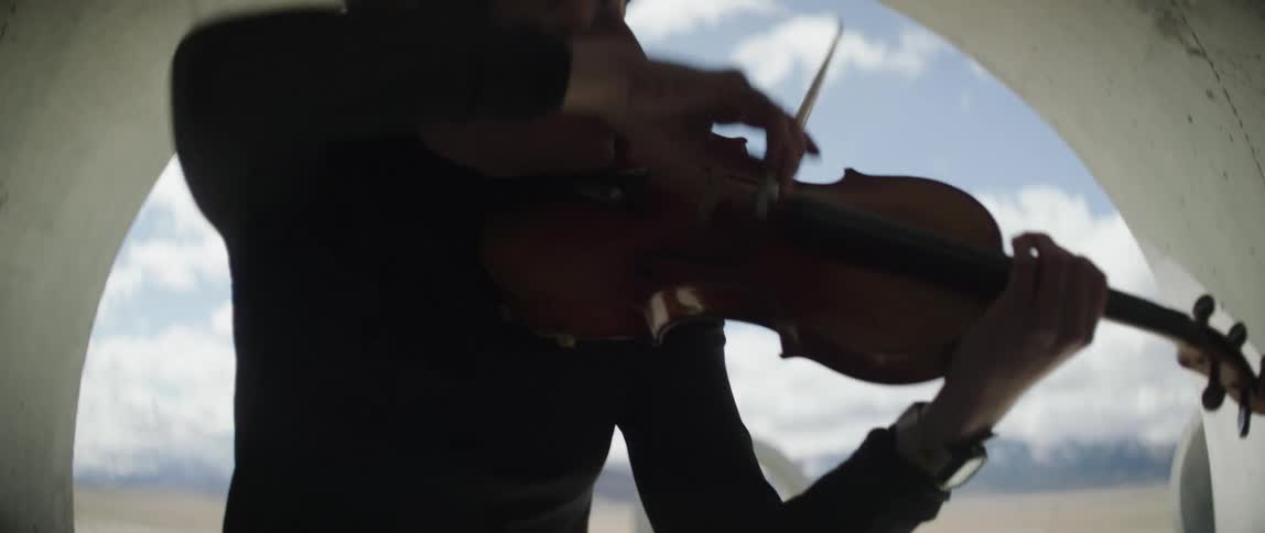 A woman is playing the violin on a windy day