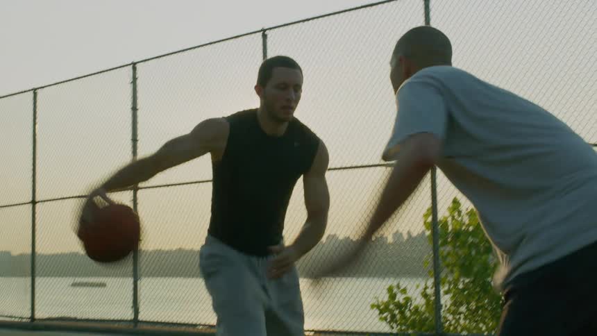 Two men play basketball on an outdoor court