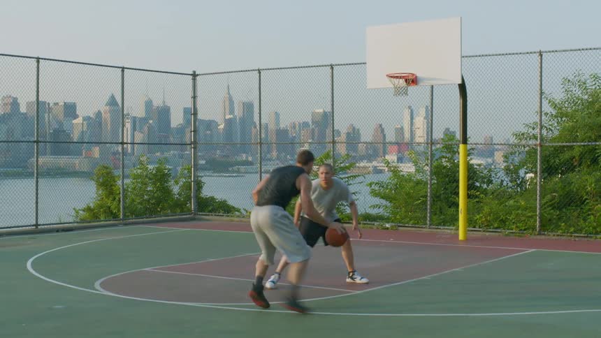 Two men playing basketball in an outdoor court