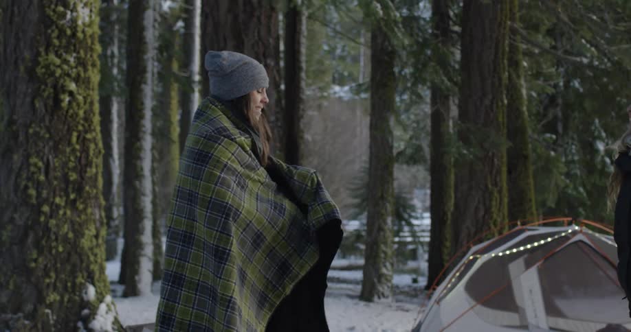 Two women talk outside next to a tent
