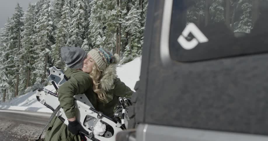 Two women hug near a vehicle on a road