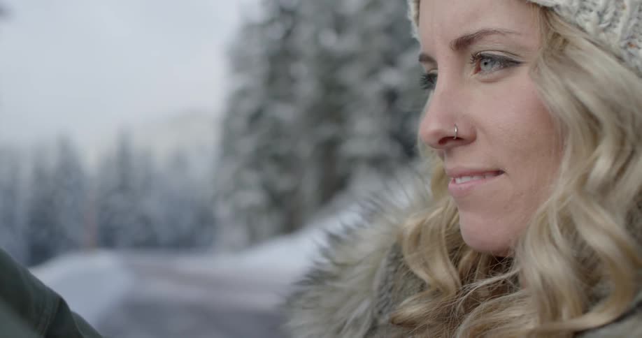 A woman with a nose ring stands outside on a winter day and smiles