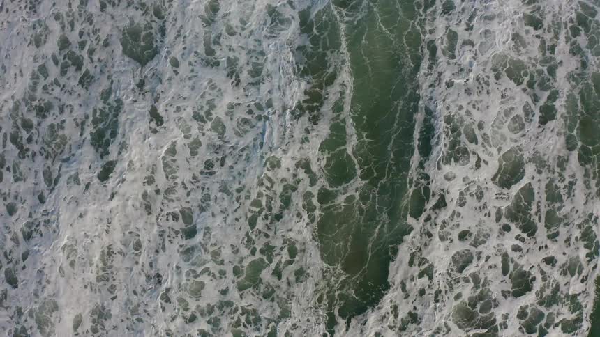 Waves are crashing over each other creating a frothy ocean