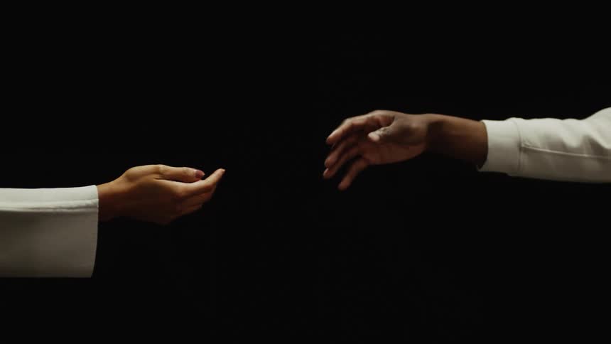 A man and woman reach their hands out towards one another