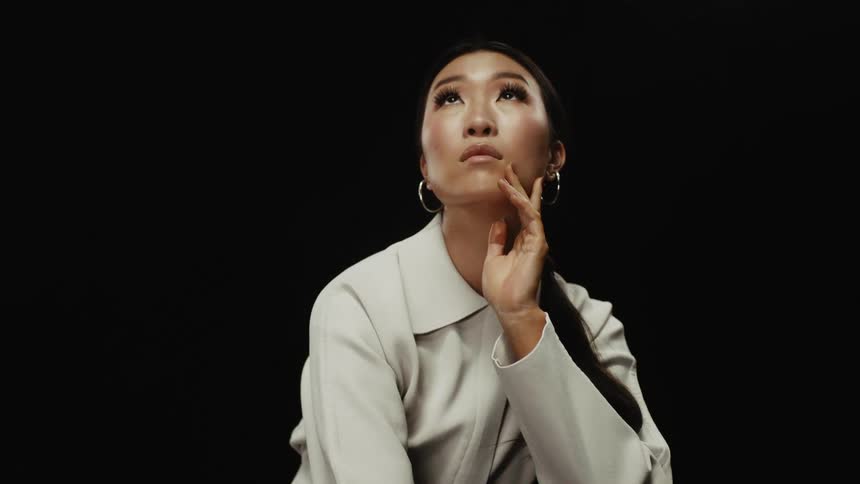 Young asian woman modeling for the camera in front of a black background