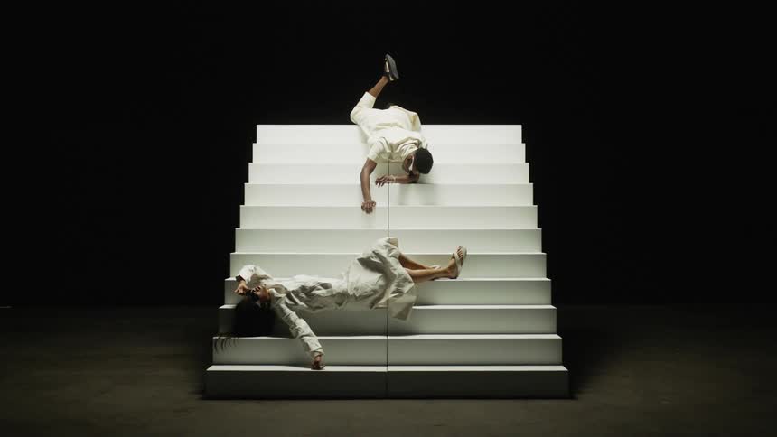 A man and a woman on a stage laying on steps with a wall in the background