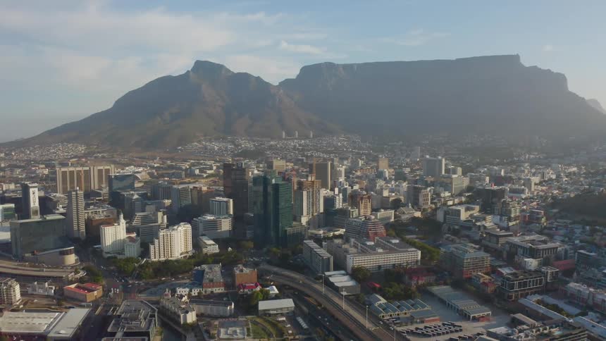 Traffic flows along busy streets through fog covered city stretching to mountains