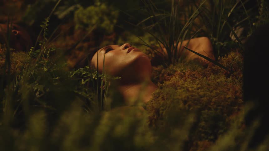 Young asian model laying on the moss between the bushes