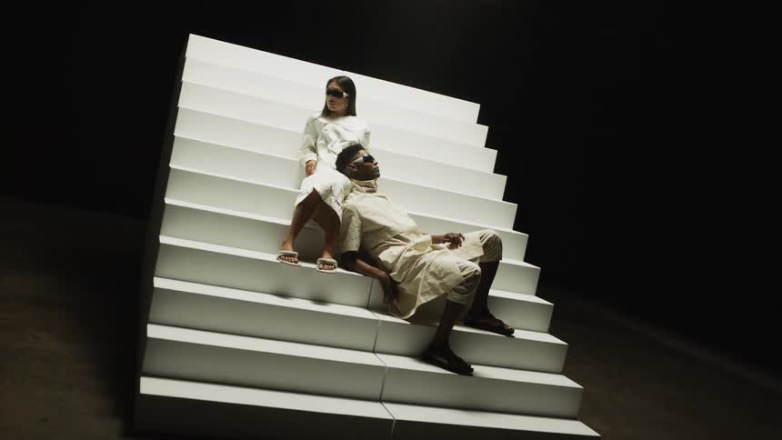 Man and woman pose sitting on stairs with mans head in womans lap on dark photo set
