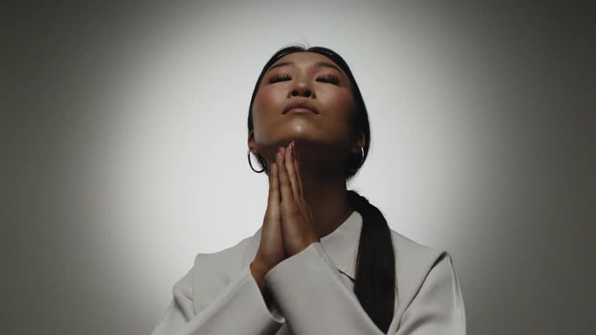 A woman is standing in a room and praying