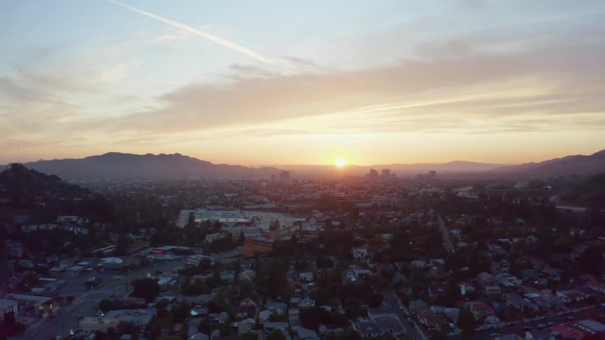 Bright sunrise shining on a busy neighborhood with mountains on the horizon