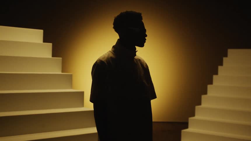 Black man wearing glasses stands between two sets of stairs