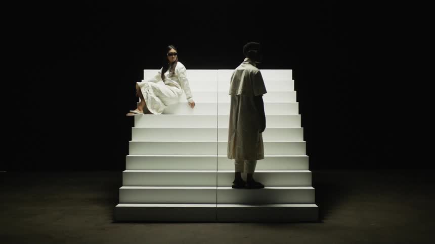 A woman is sitting on a staircase and a man is standing