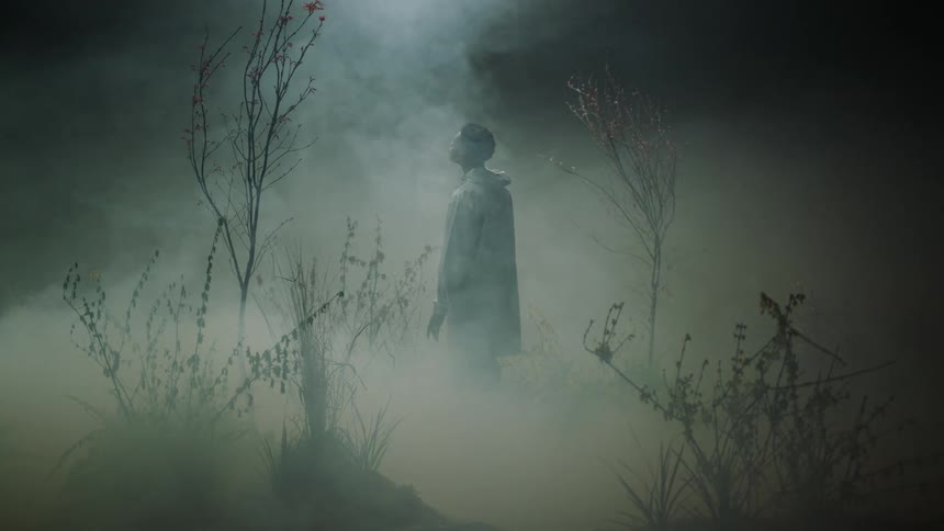 A man is standing outdoors at night in the fog