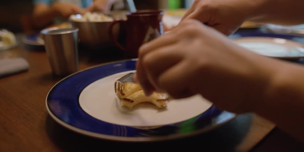 Parent cuts pancake into squares as other family members move around table