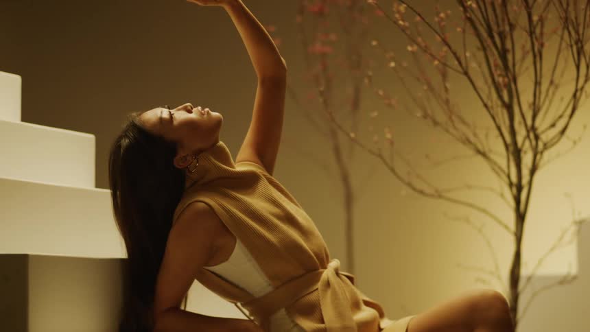 Fashion modelposes against white stairs with small trees in background near wall