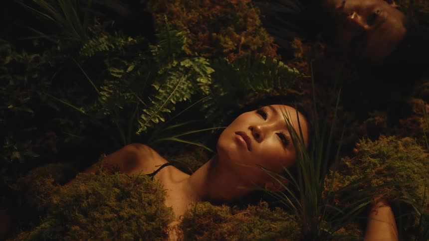 Two models laying on the forest floor covered in moss