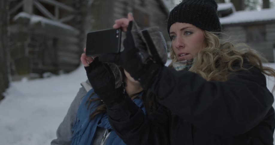 Two women pose for a photo using a phone