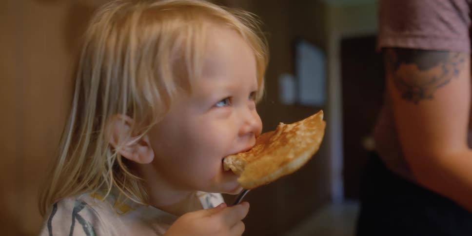 A little girl is eating a slice of pizza with her grandmother
