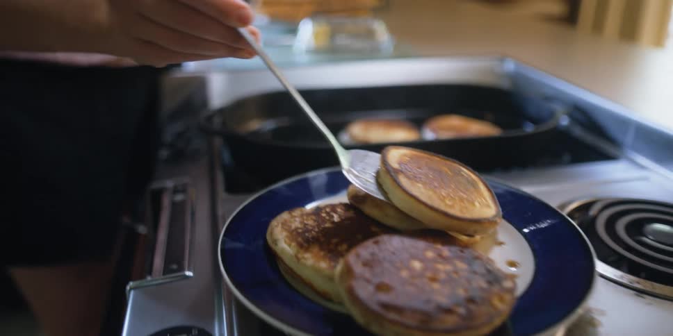 A woman is cooking pancakes on her stove