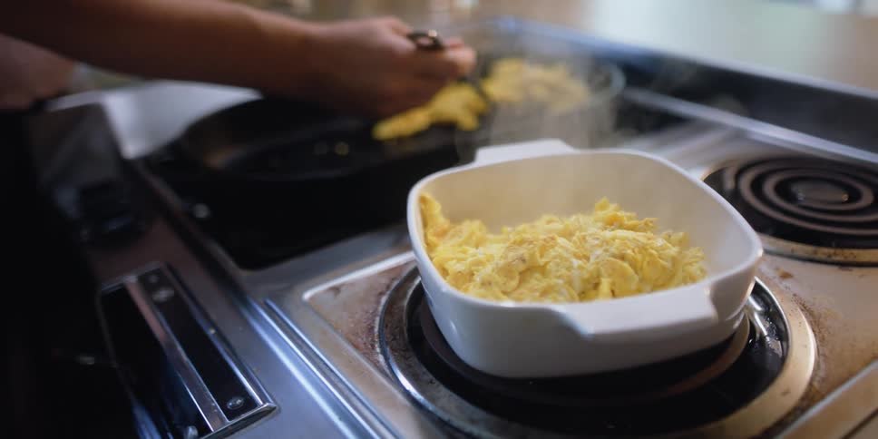 A person is cooking eggs in their home