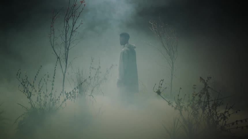 A man standing in a smoky errie area