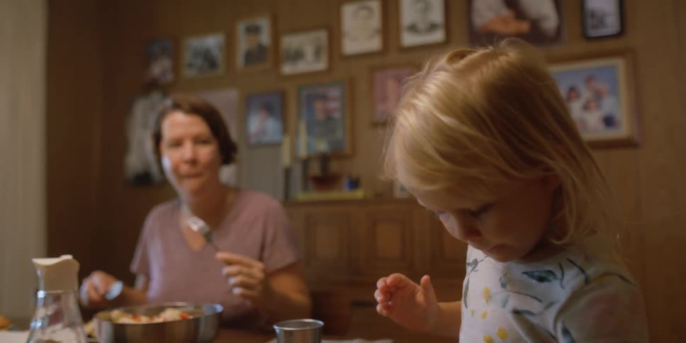 A woman and young girl sit at a dinner table eating together