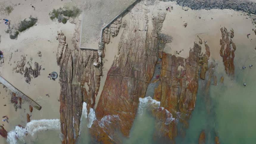 People on a beach with sand rocks and waves of water