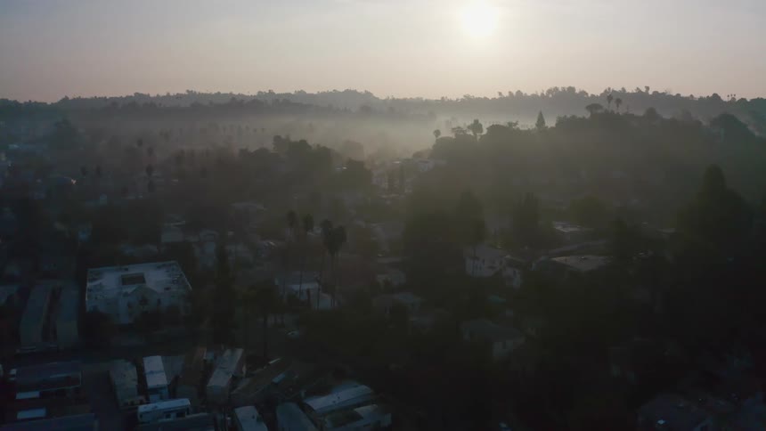 Sun rising over a neighborhood with mountains and hills