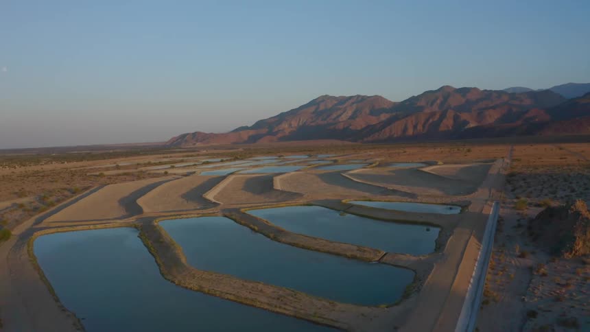 Water reservoir with nearby mountains under a clear blue sky