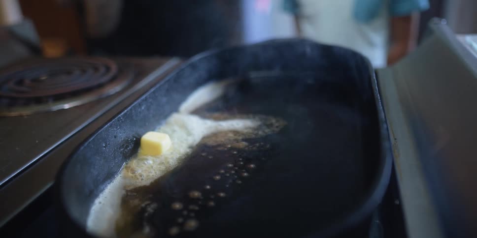 Butter melts on a hot skillet set on a stove top