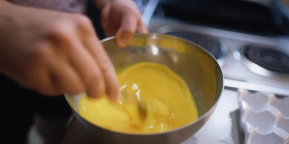 A person beating eggs in the kitchen