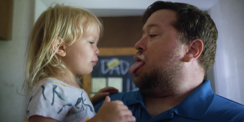 Father and daughter playfully gesturing at each other at home