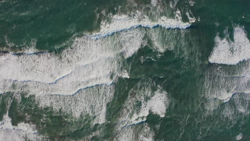 Multiple sets of waves sweep across the ocean surface and head towards the shorline