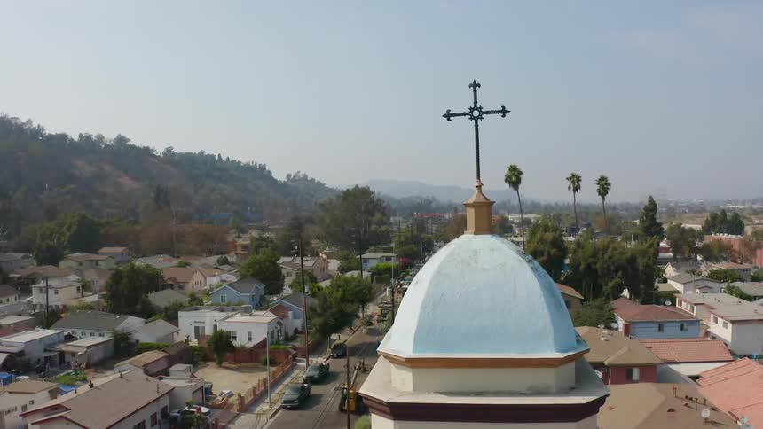 Looking up over a church steeple a town is revealed that is lush and green